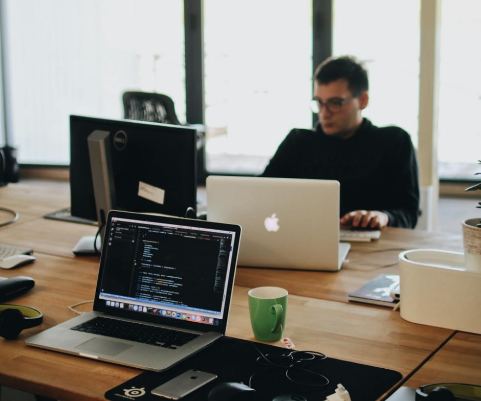 A Person sitting in front of Mac laptop and working