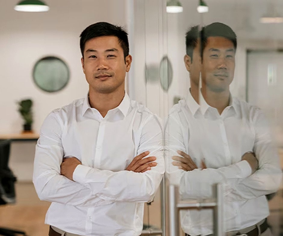 person standing next to glass door smiling