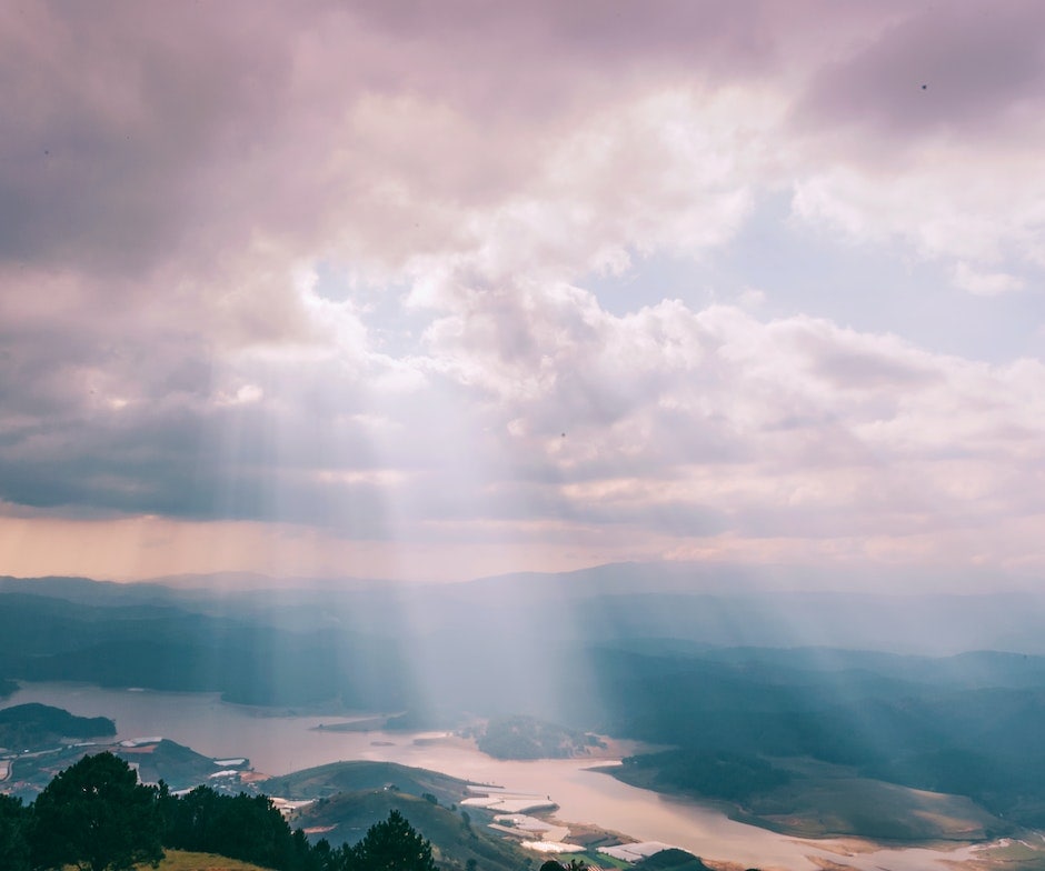 sun shining through clouds onto land below
