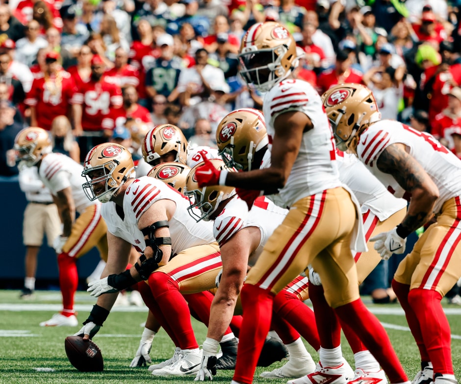 I giocatori dei San Francisco 49ers erano allineati sulla linea di scrimmage durante una partita, preparandosi per lo snap.