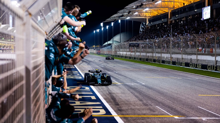 fans waving to f1 cars on side of racetrack