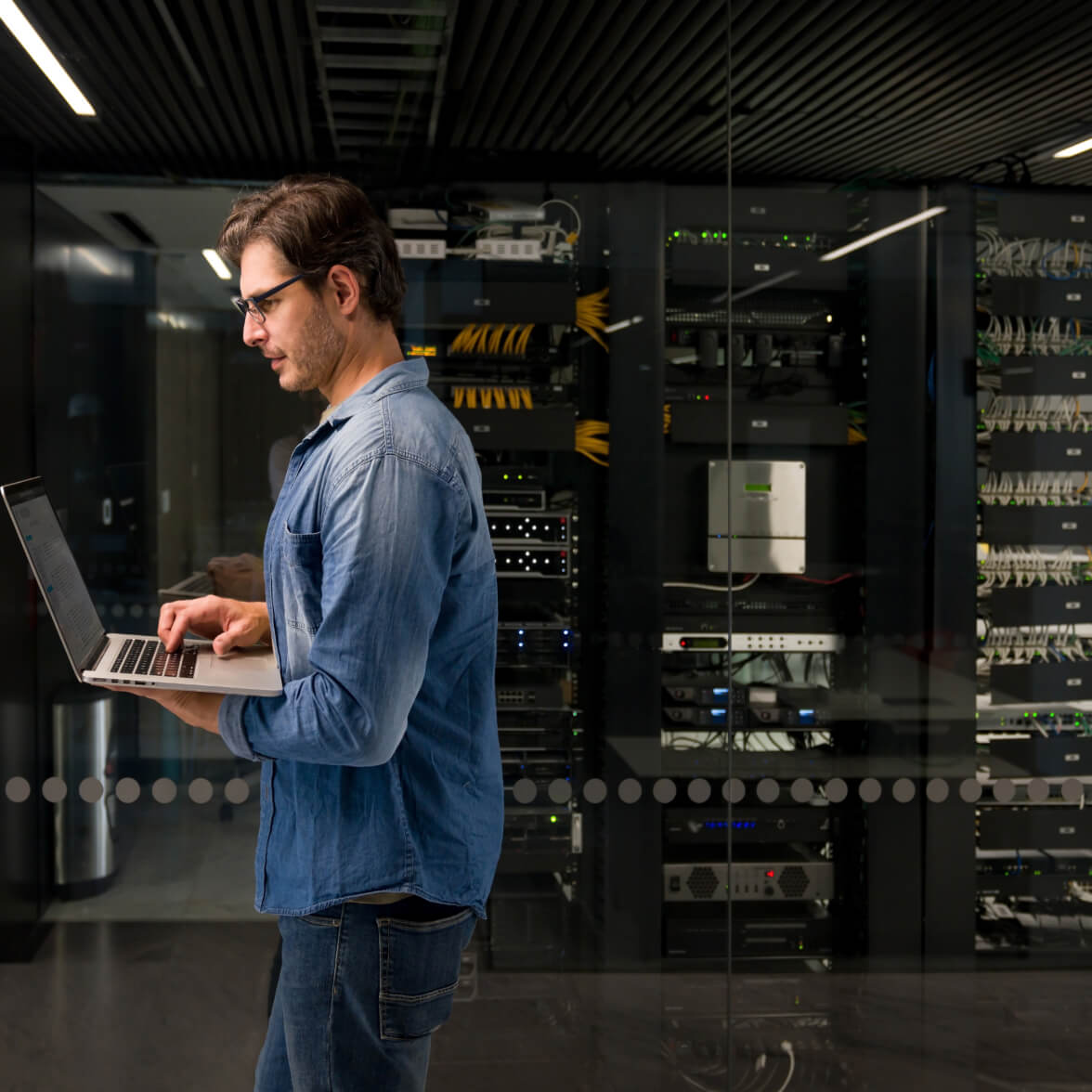 personne tenant un ordinateur portable et marchant dans un data center