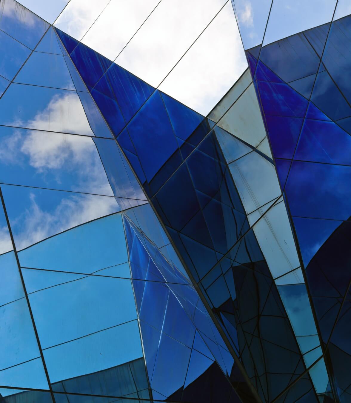 Detail of a geometric building reflecting clouds