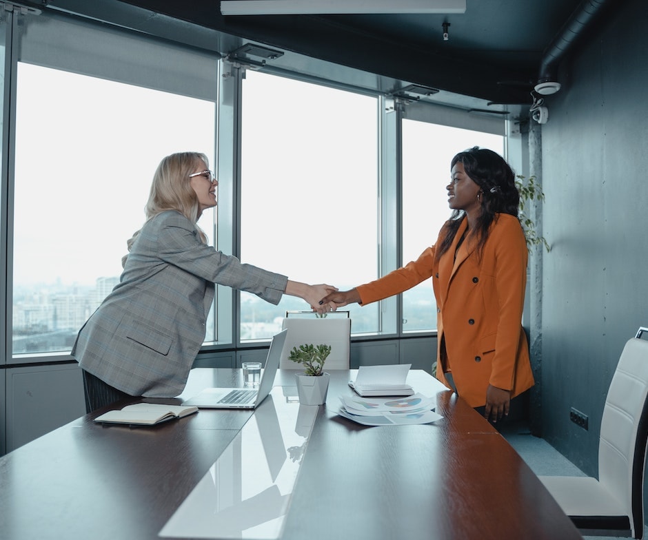 two people at a desk shaking hands