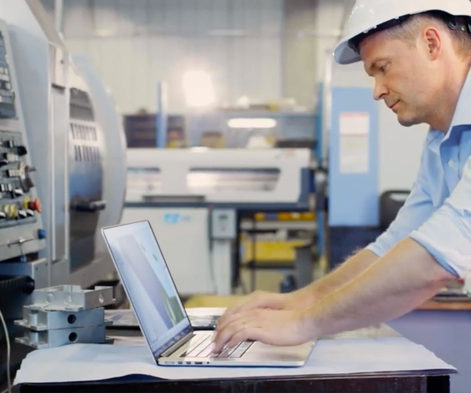 Am Laptop arbeitender Mann mit Schutzhelm