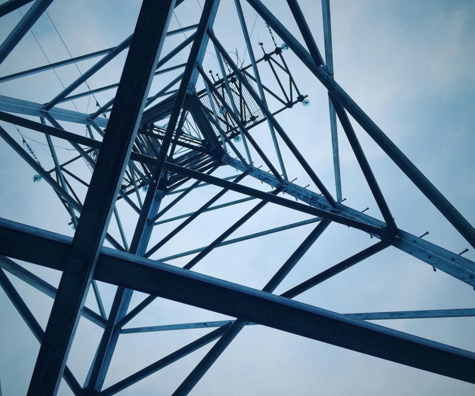 Close-up view of a steel transmission tower structure against the sky.