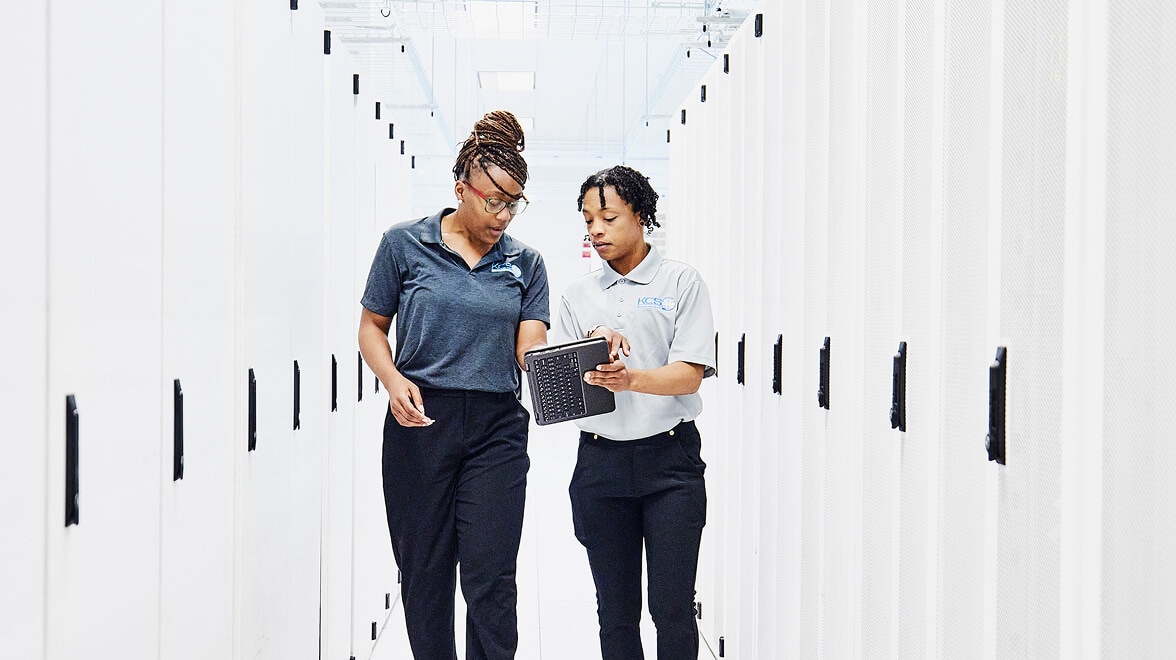 Two persons discussing by looking into the tab and walking