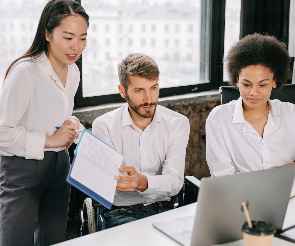 Three people meeting at a table on laptop