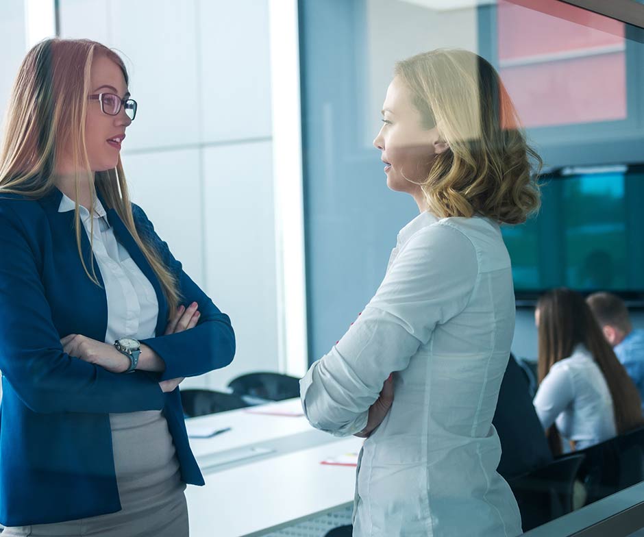 two women coworkers chatting together in conference room