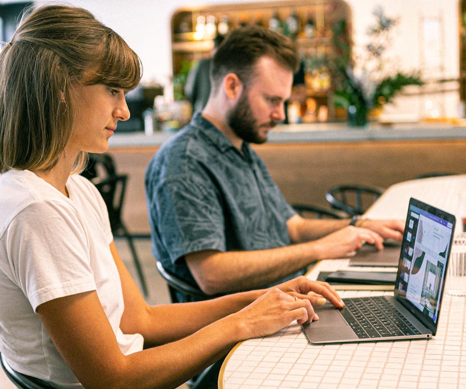 Two people working on laptop in office
