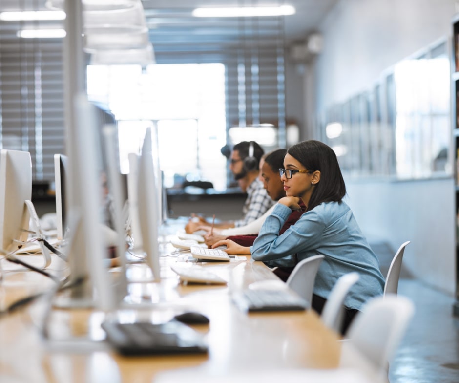 people sitting inside library in front of laptop and taking notes
