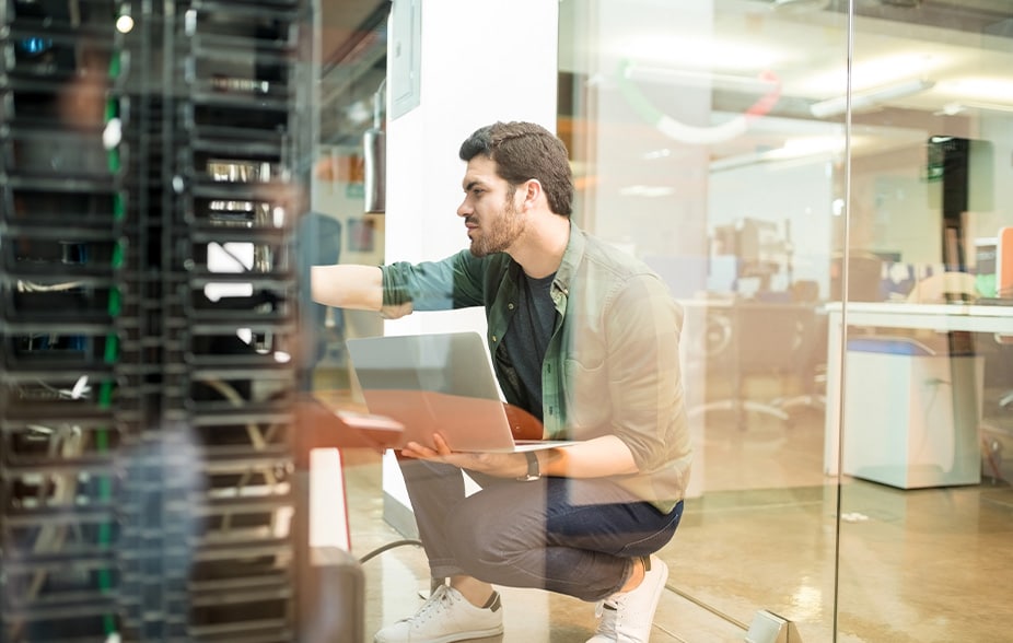 Person, die vor einem Server-Rack hockt