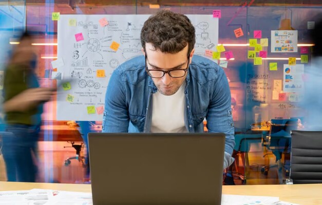 Person looking at laptop with creative board in background