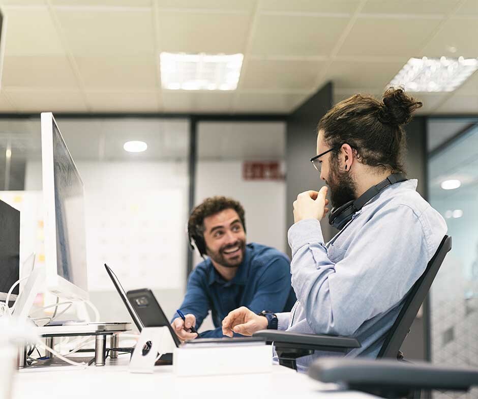 two guys sitting and conversing at office desk