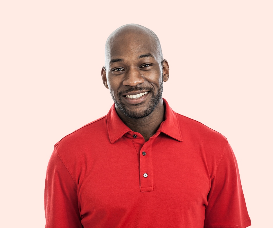 Hombre sonriente con camisa roja sobre un fondo melocotón