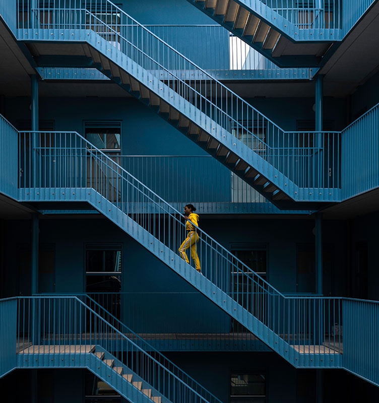 Person walking up an exterior blue metal staircase of a multi-level building