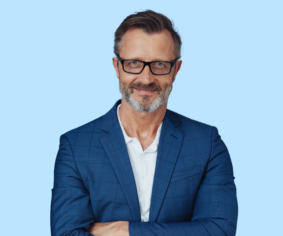 spectacled man with arms crossed, wearing blue sports jacket over white polo shirt