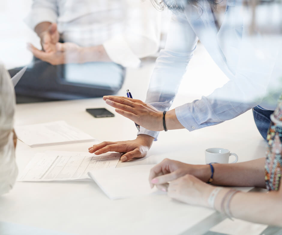 people handling paperwork at conference table