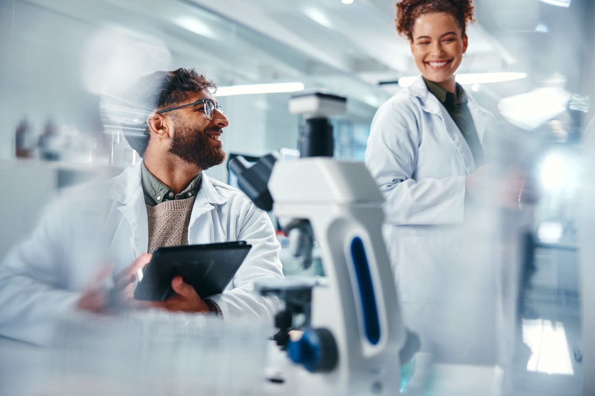 Tablet, scientist and team with smile, medical research and man for results of test and talking. Lab, online and conversation for medicine of healthcare, pharmaceutical and collaboration for science