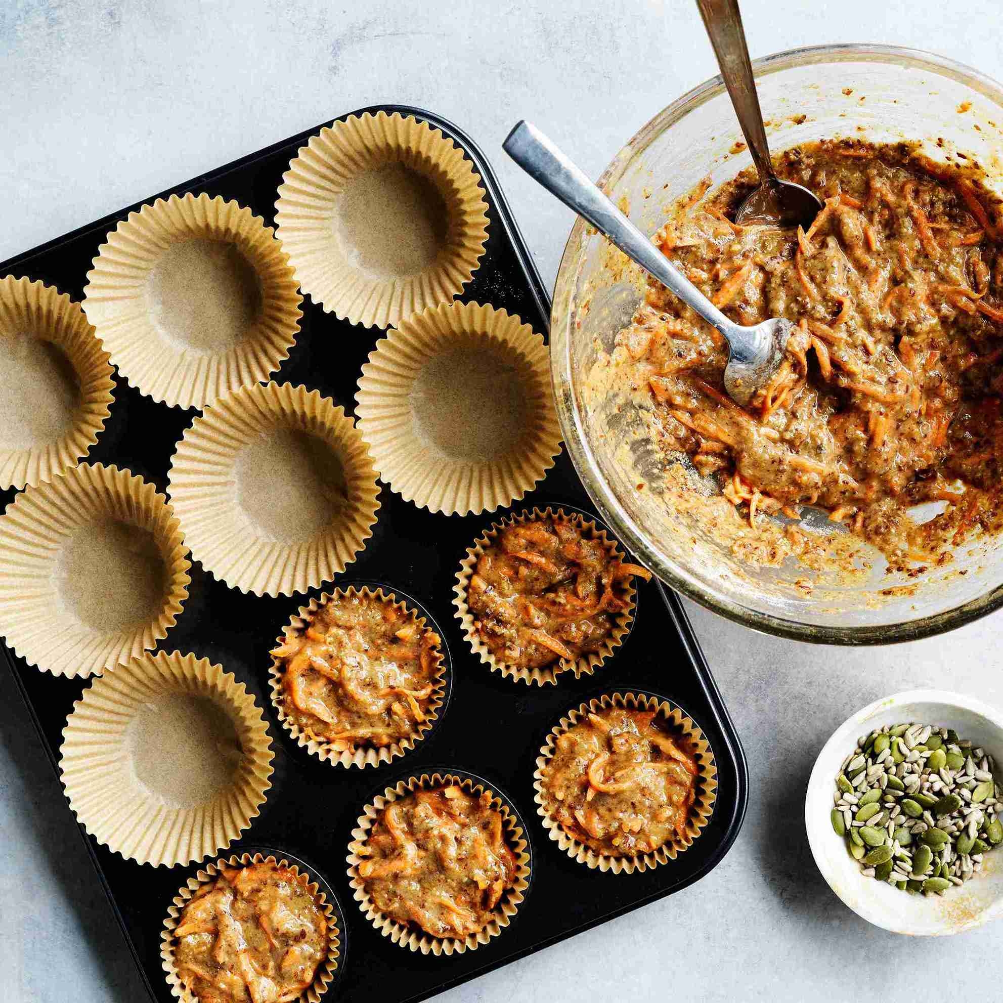 unbaked muffins in paper cases topped with seeds, ready for the oven