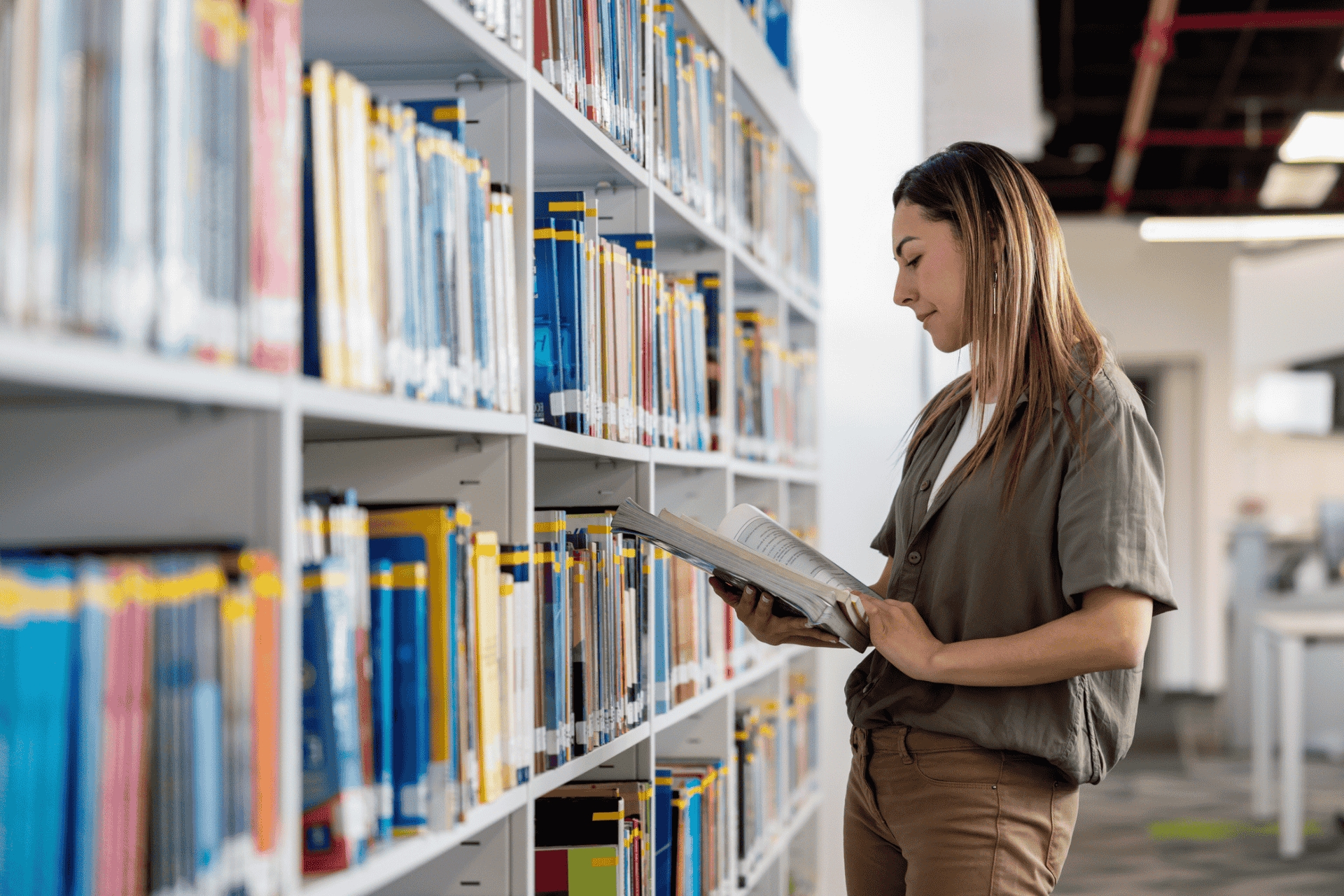 Happy woman searching for a book at the library while researching heart health