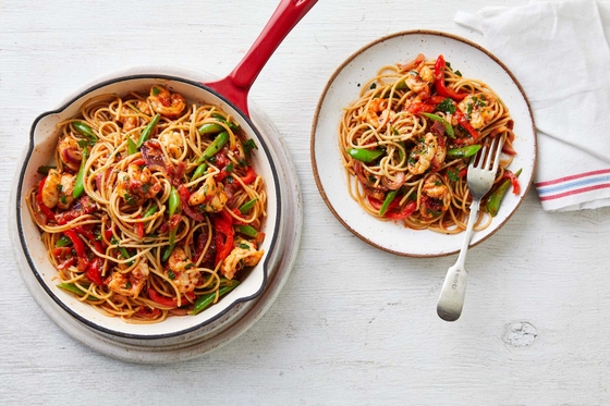 Two bowls of spaghetti topped with peppers and prawn