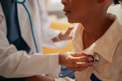 Doctor holding stethoscope on patient's chest