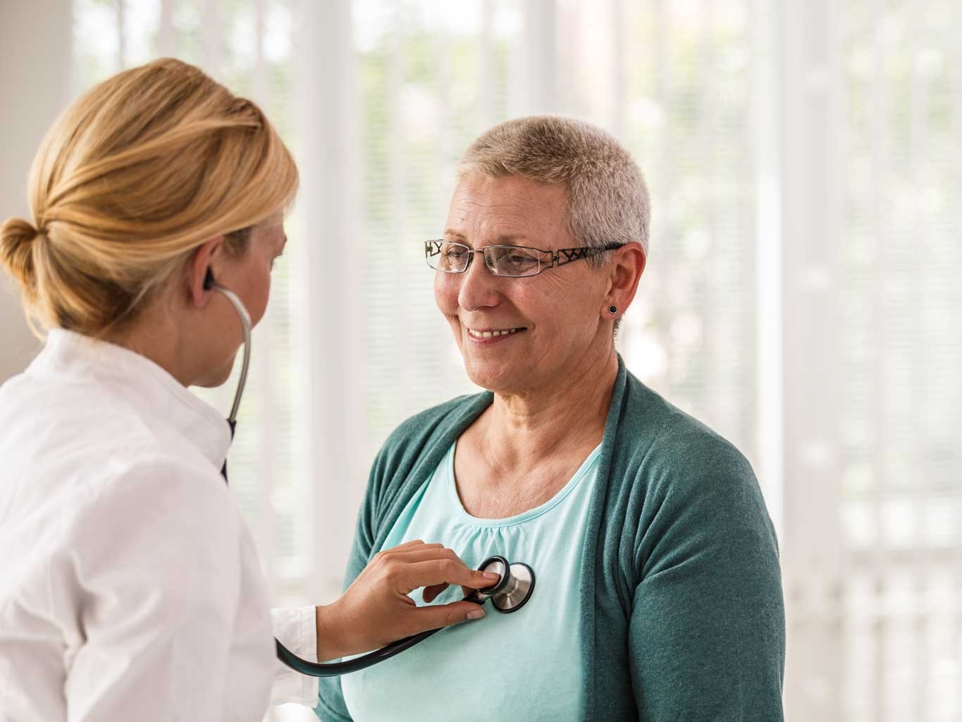 Female doctor using stethoscope while examining patient.