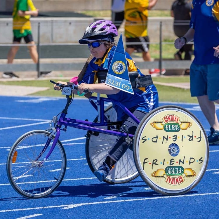 Participant using a racing wheelchair during an athletics event on a running track.