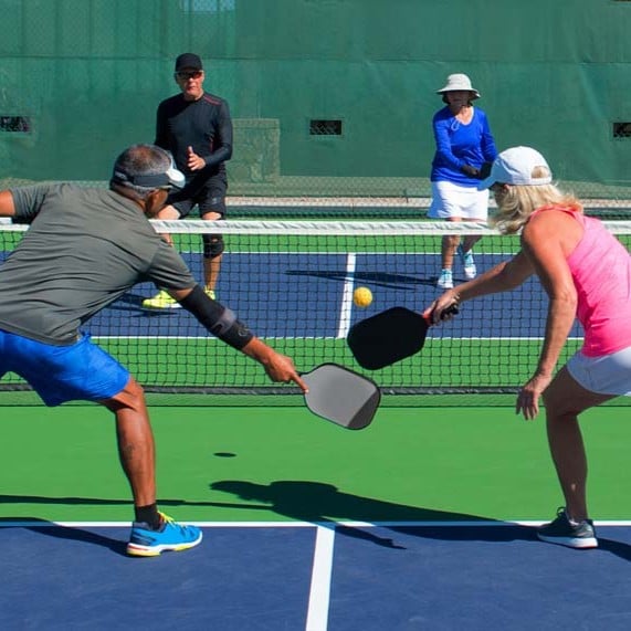 Adults playing pickleball on an outdoor court