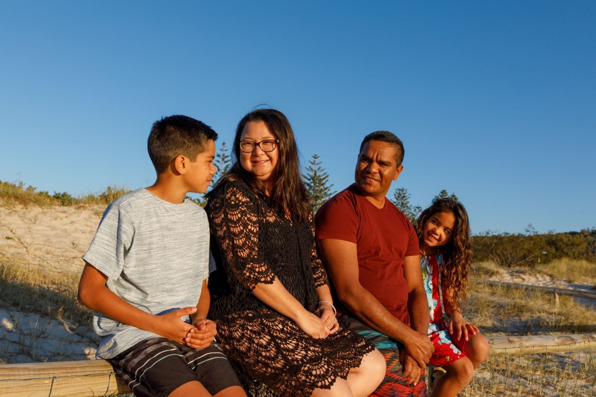 A multi-racial family sitting in the sunshine on the beach