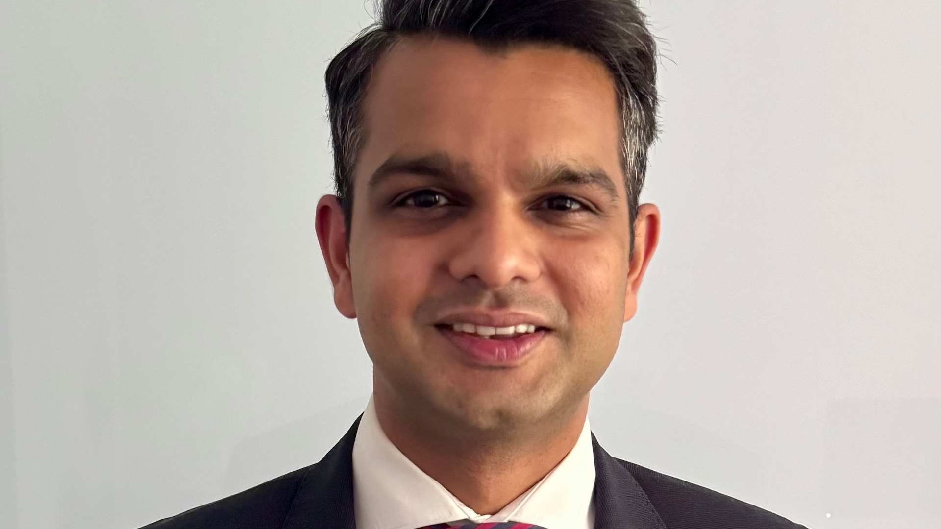 Chinmay Khandkar smiling while standing in a suit