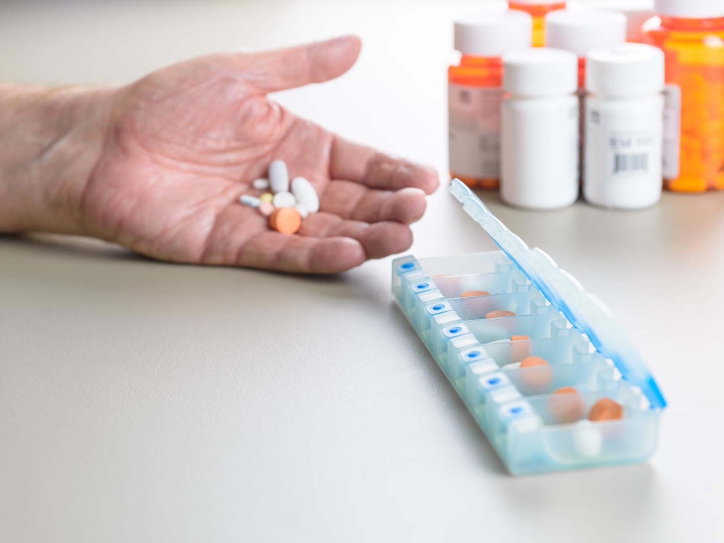 hand with pills and surrounded by medicine