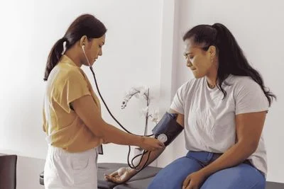 Female health professional standing checking patient's blood pressure