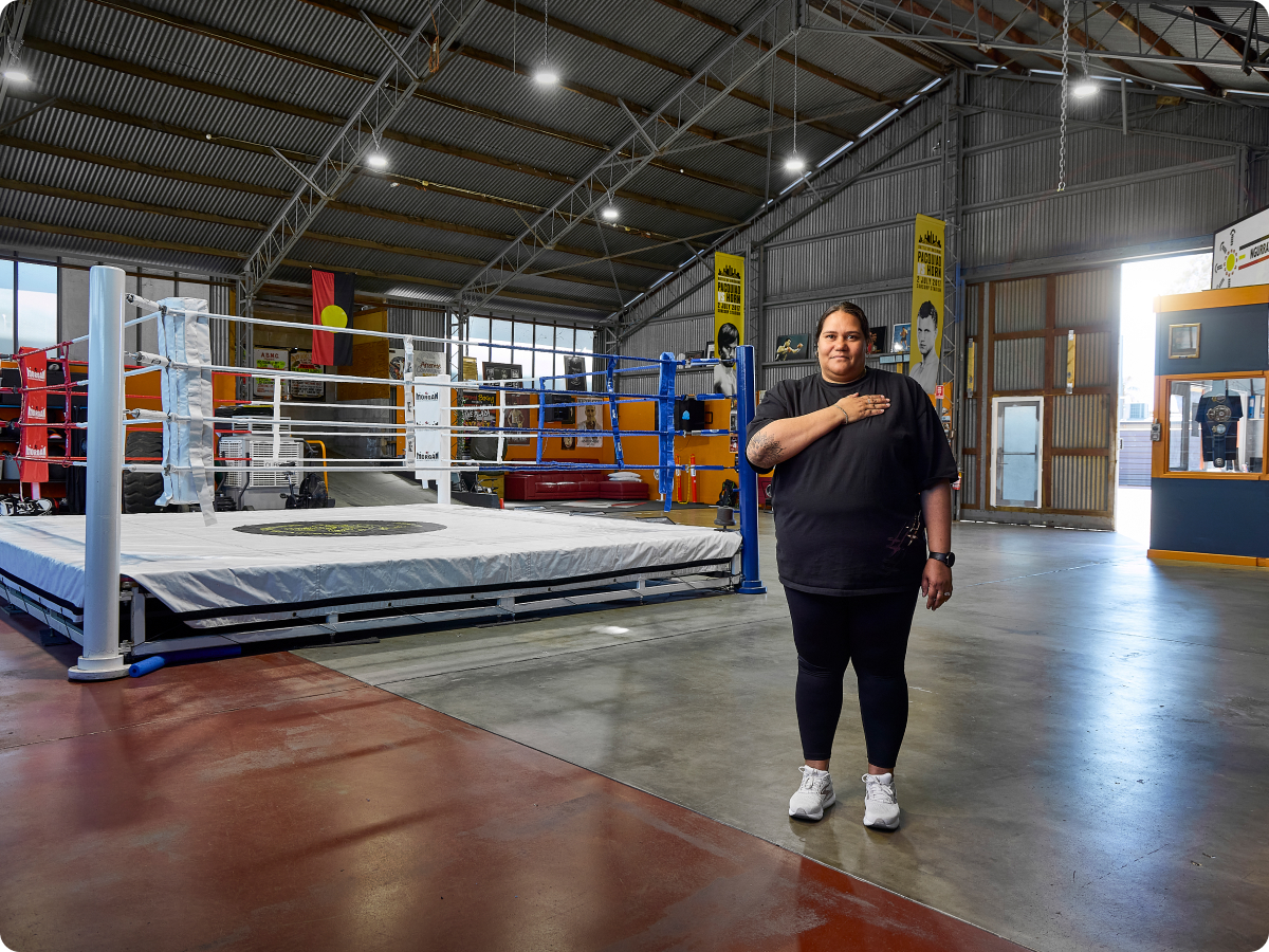 first nations woman standing in a empty boxing gym with her hand on her heart 