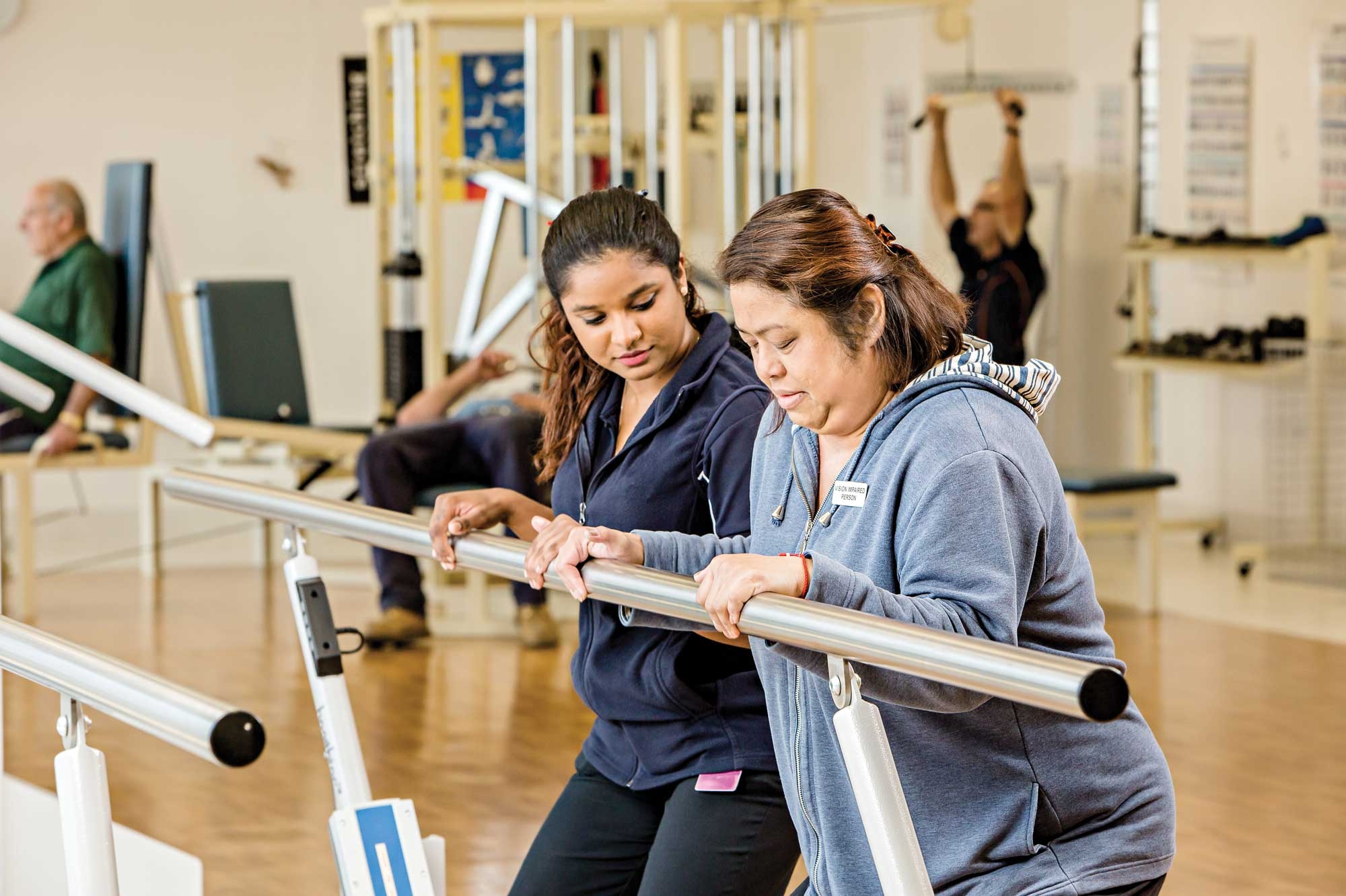 Two women, a physiotherapist and another who is living with a heart condition, holding onto an exercise bar