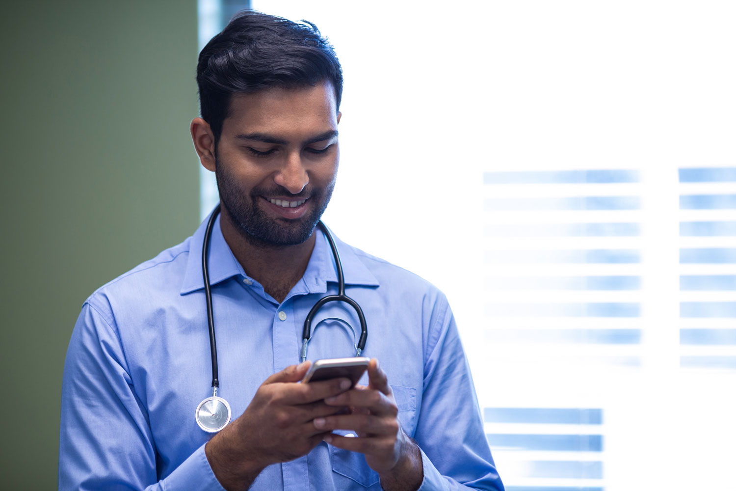 Male health professional looking at his phone as he does his online training