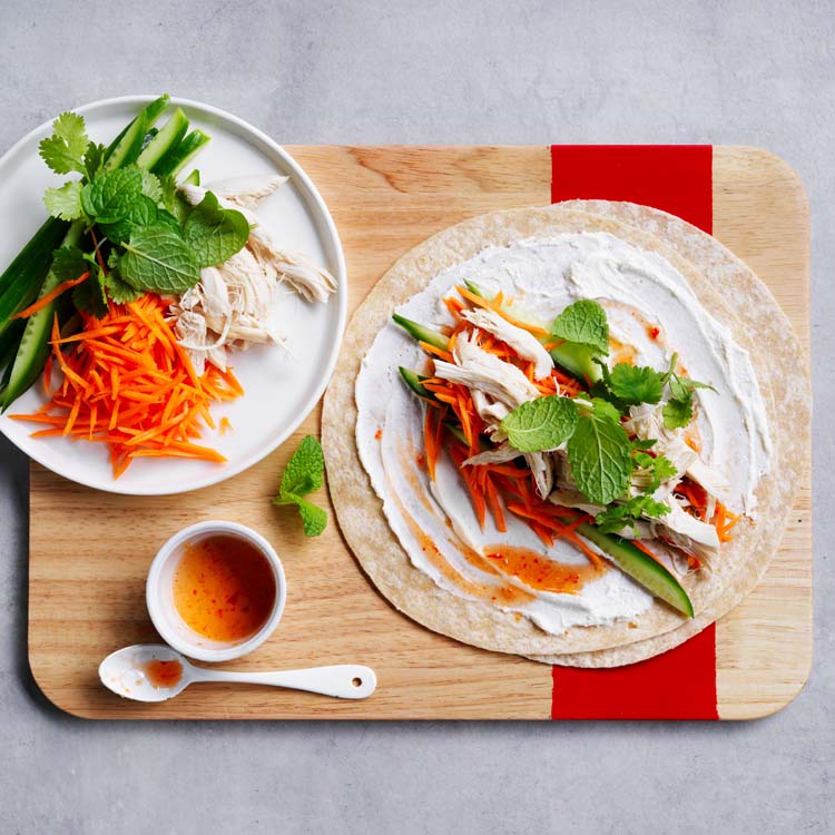 Chicken and vegetables arranged on wraps with fresh herbs