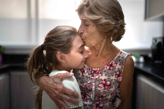 Grandma kissing the forehead of her granddaughter as they embrace