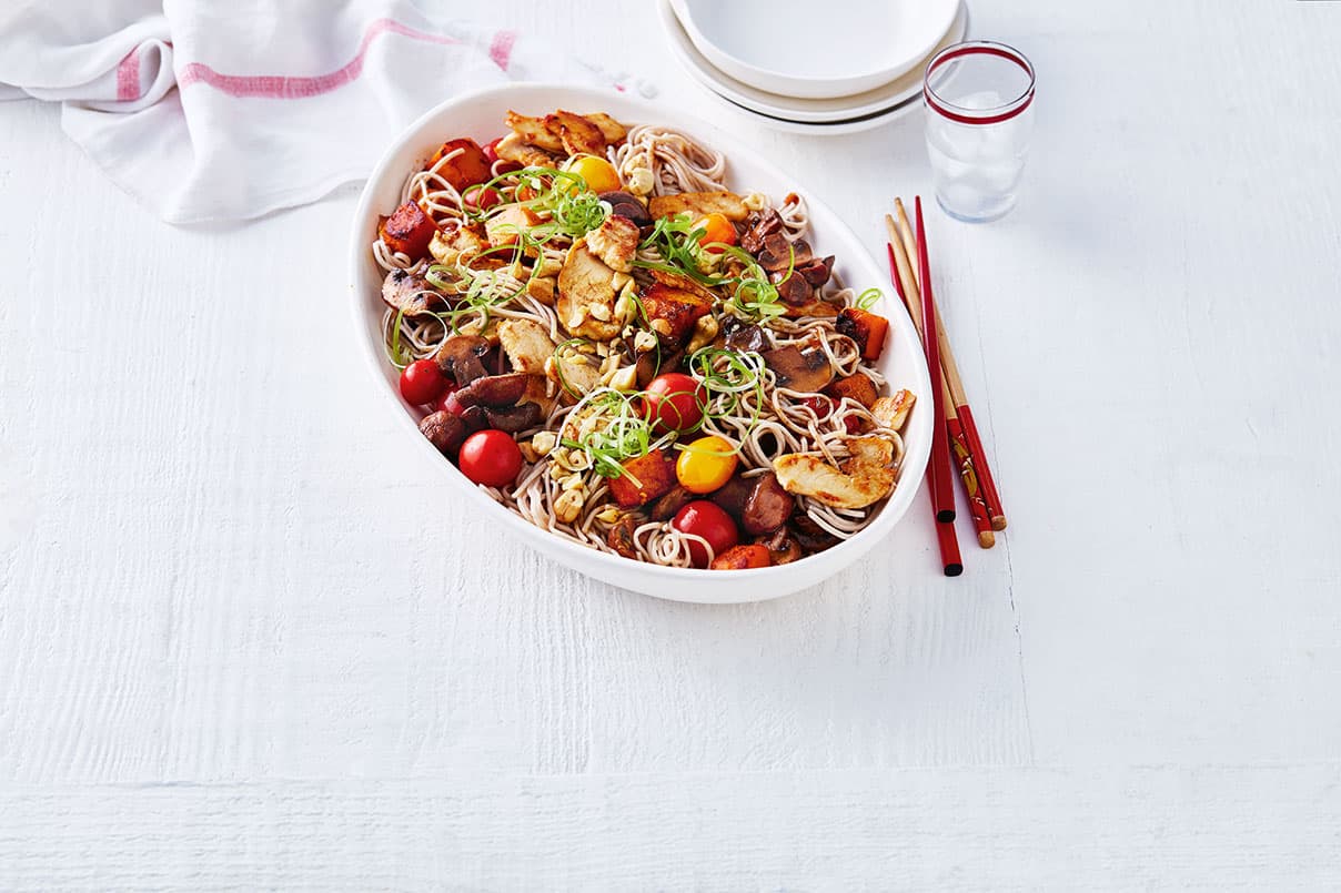 A bowl of chicken and pumpkin stir-fry on a table with chopsticks