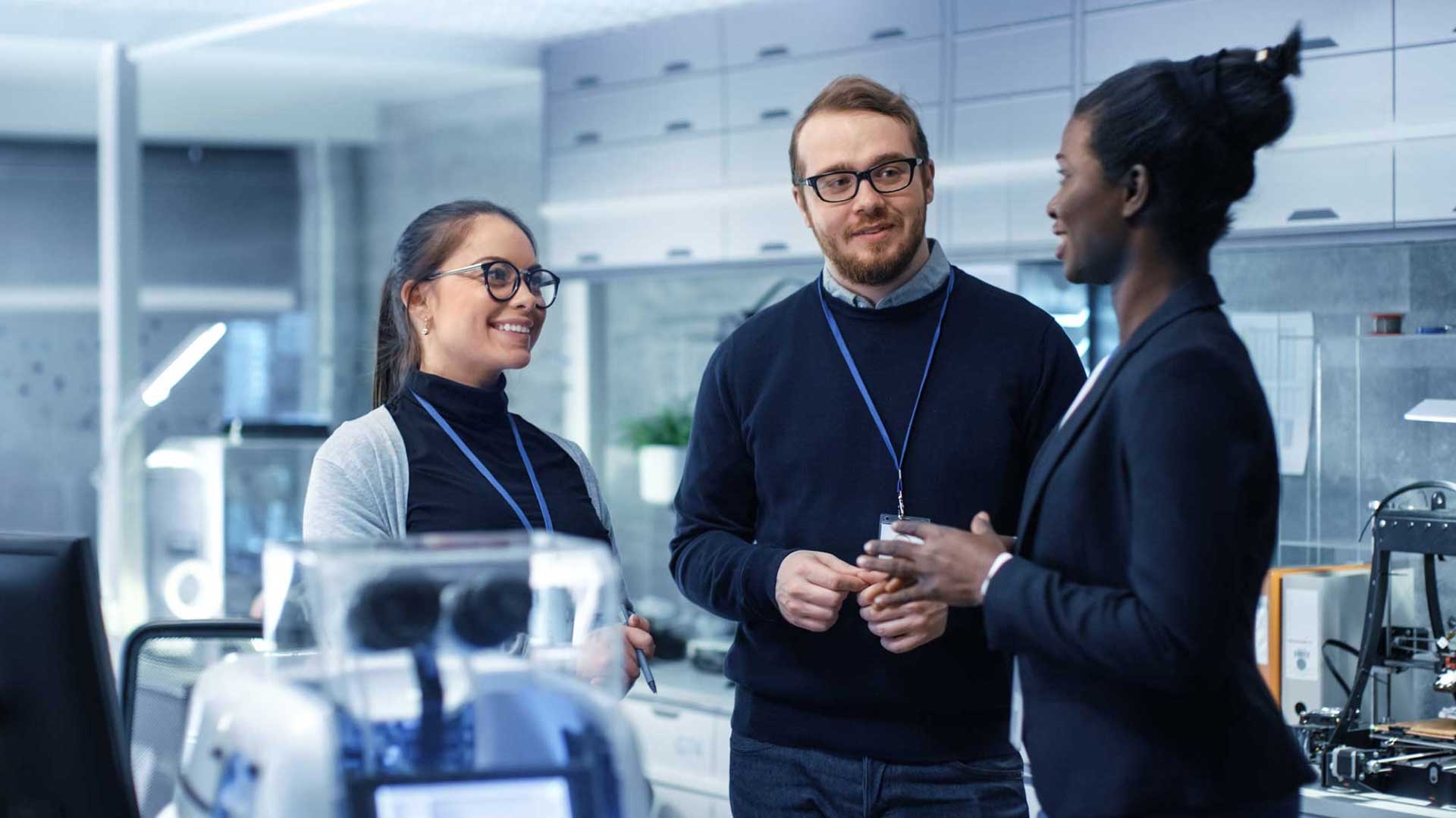 Group of three researchers discussing work in an office breakout space