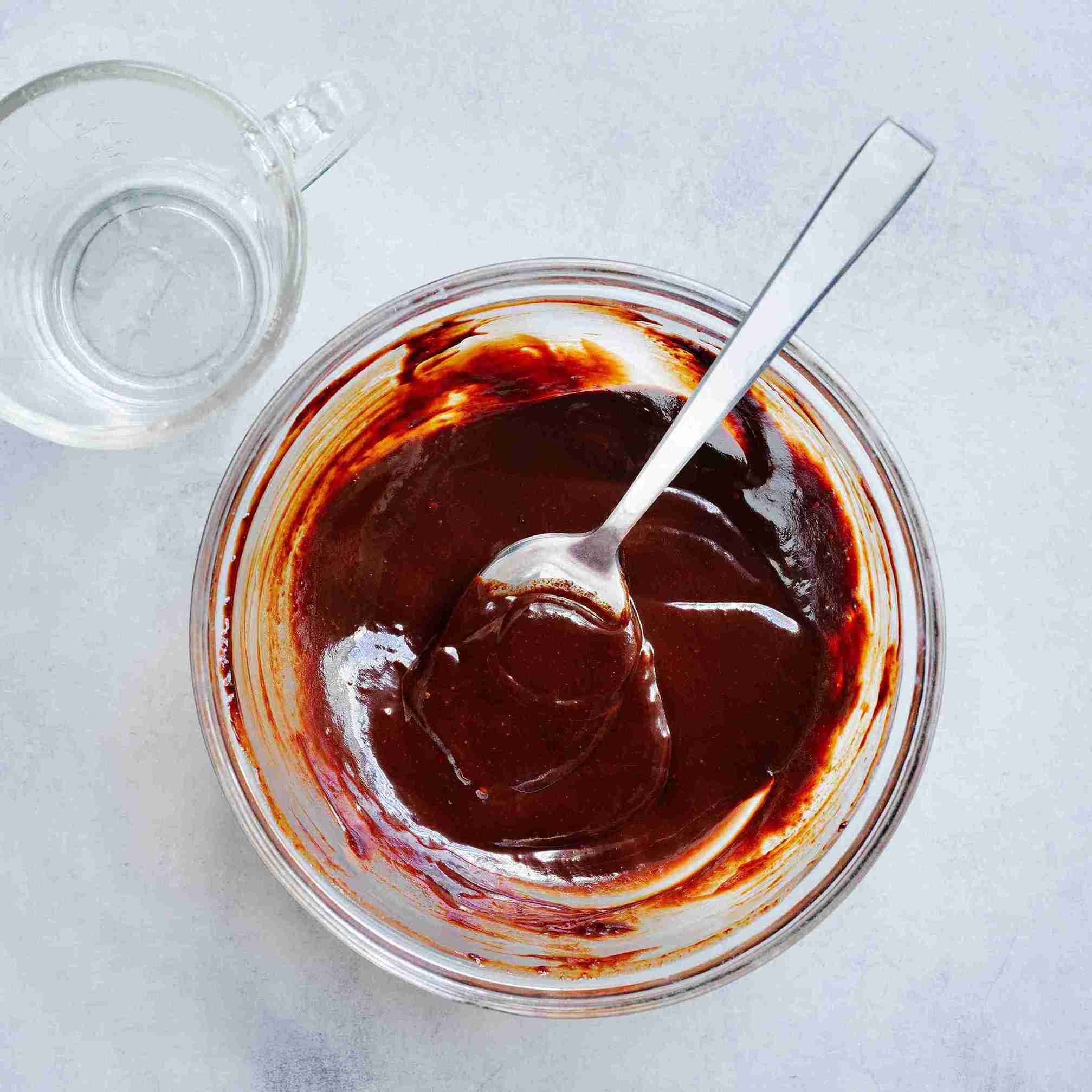 melted chocolate being stirred in a bowl over simmering water