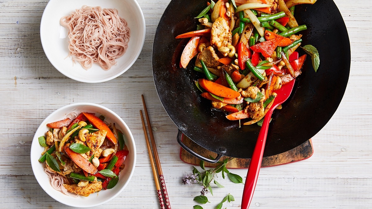 Chilli basil chicken noodles in a wok and a bowl