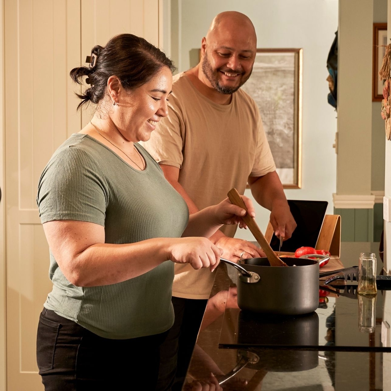 A couple preparing fresh vegetables together in a bright kitchen, including broccoli, carrots, and peppers — making heart-healthy meals at home.