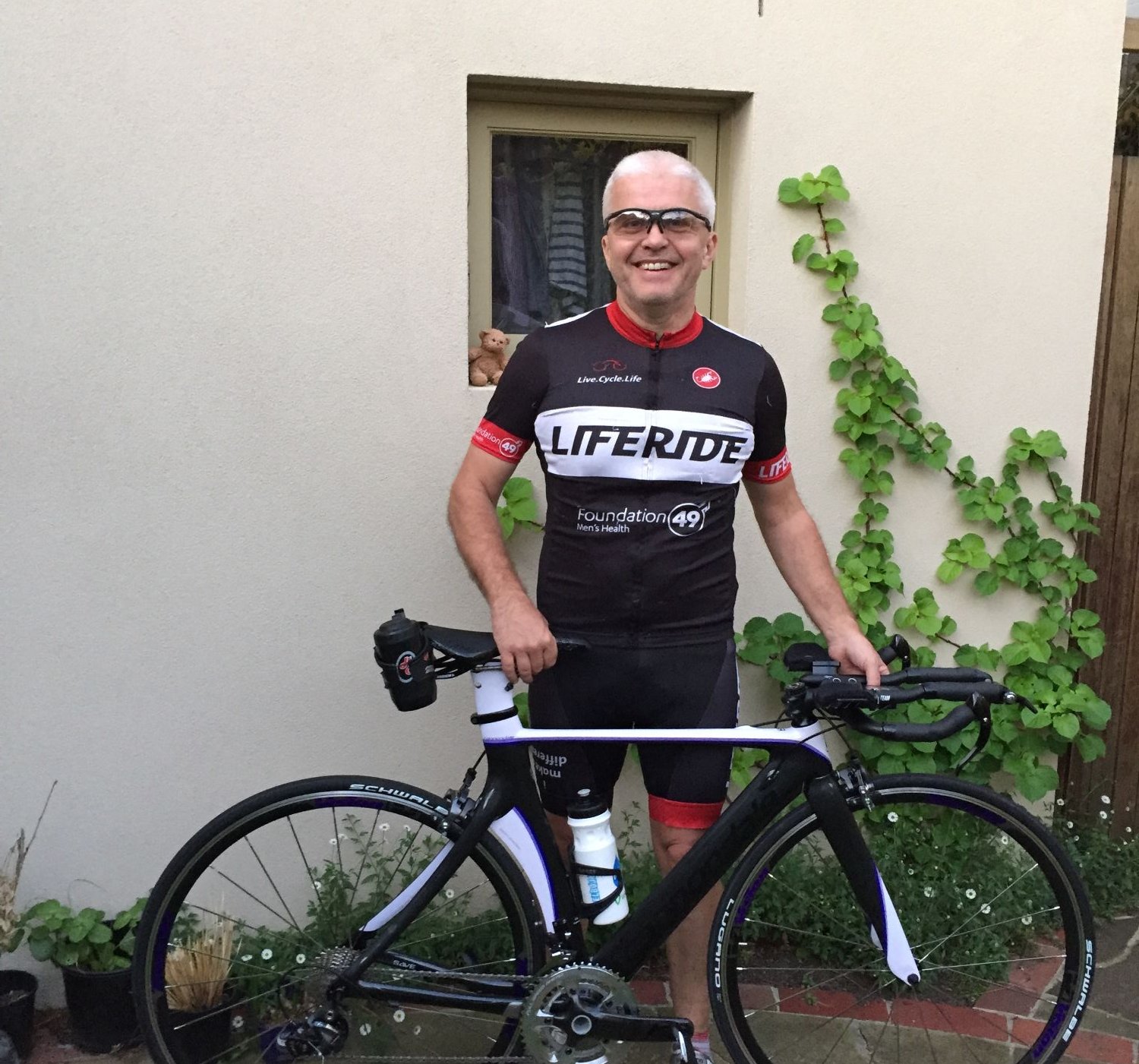 David Lloyd standing outdoors with a road bike, wearing cycling gear
