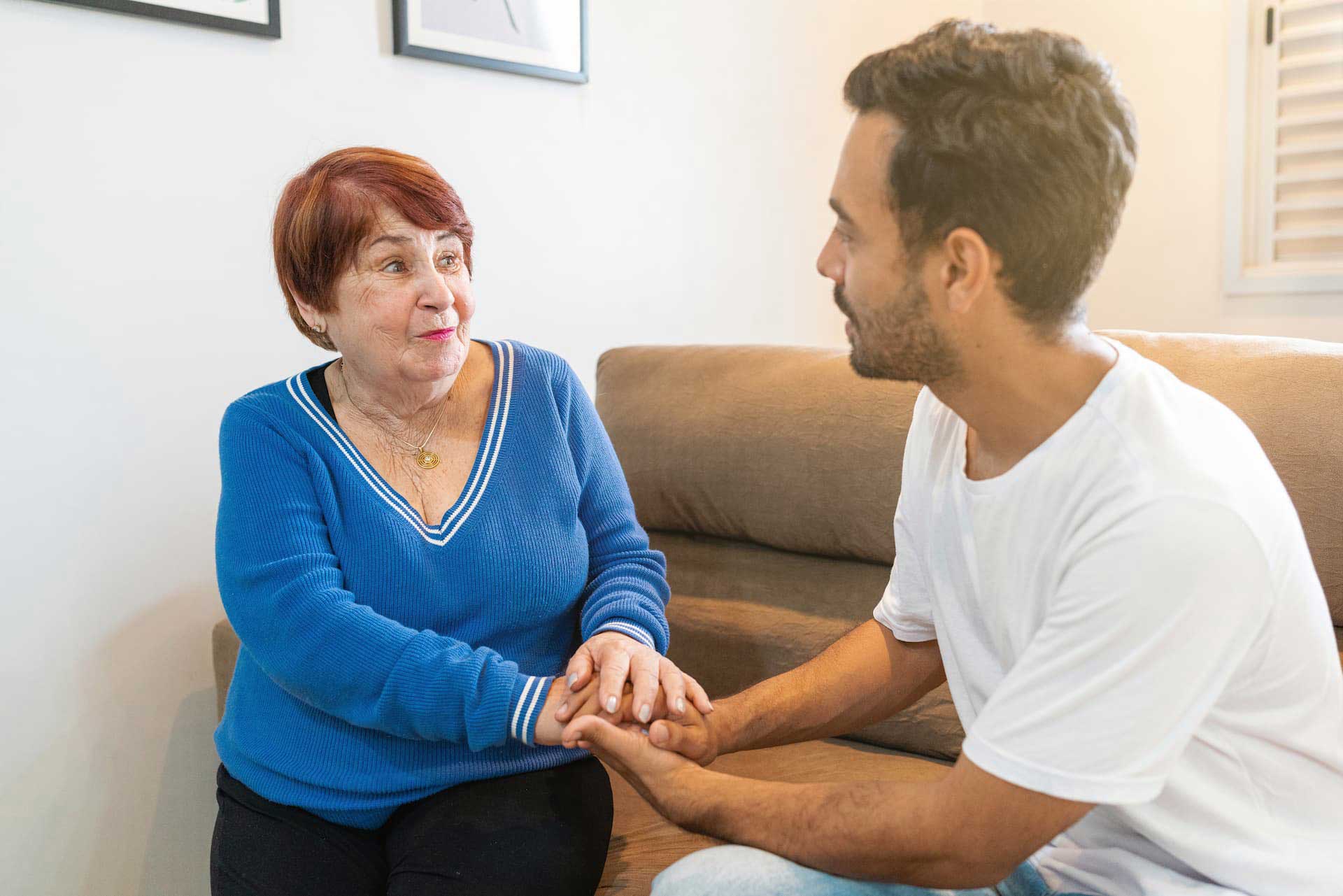 A mature woman in blue v neck sweater is holding her son's hand