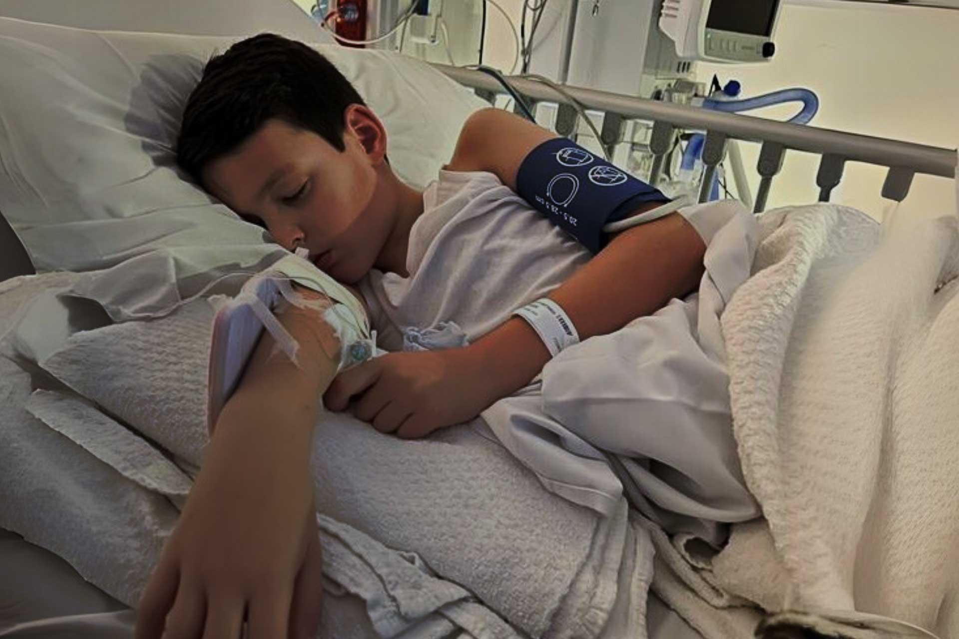 Young George who suffered a sudden cardiac arrest, lying in hospital bed 
