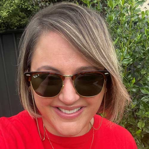 A photograph of Teresa Gadaleta, wearing a Heart Foundation t-shirt. Teresa has tanned skin, a blond bob, a big smile and sunglasses.