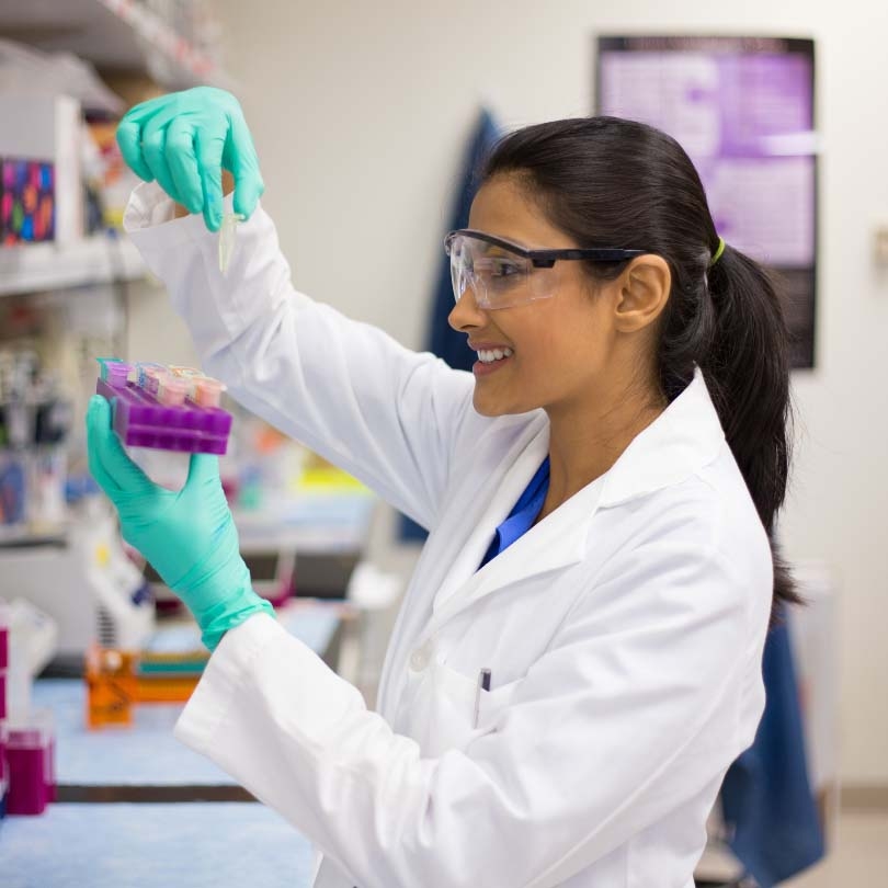 Female scientist in lab wearing protective eyewear and holding test tube