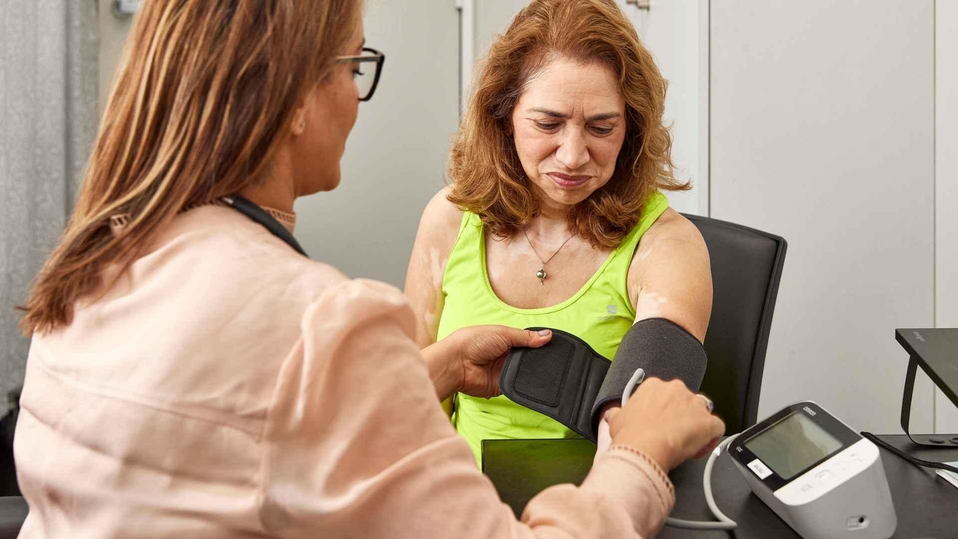 A female GP doctor is checking a woman's blood pressure.